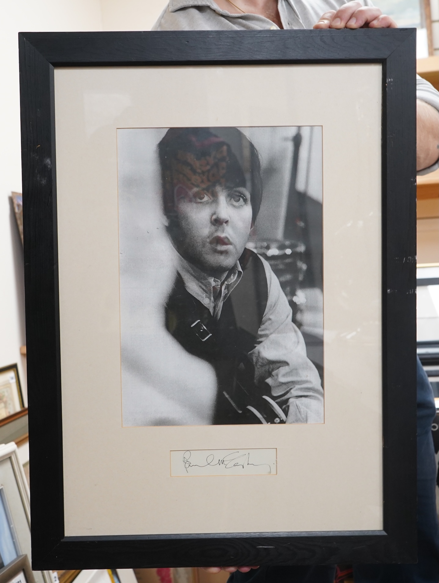 A framed autograph of Paul McCartney, signed in black ink, mounted below a black-and-white photograph of McCartney taken from a 1960s image, dimensions of frame; 66 x 48cm